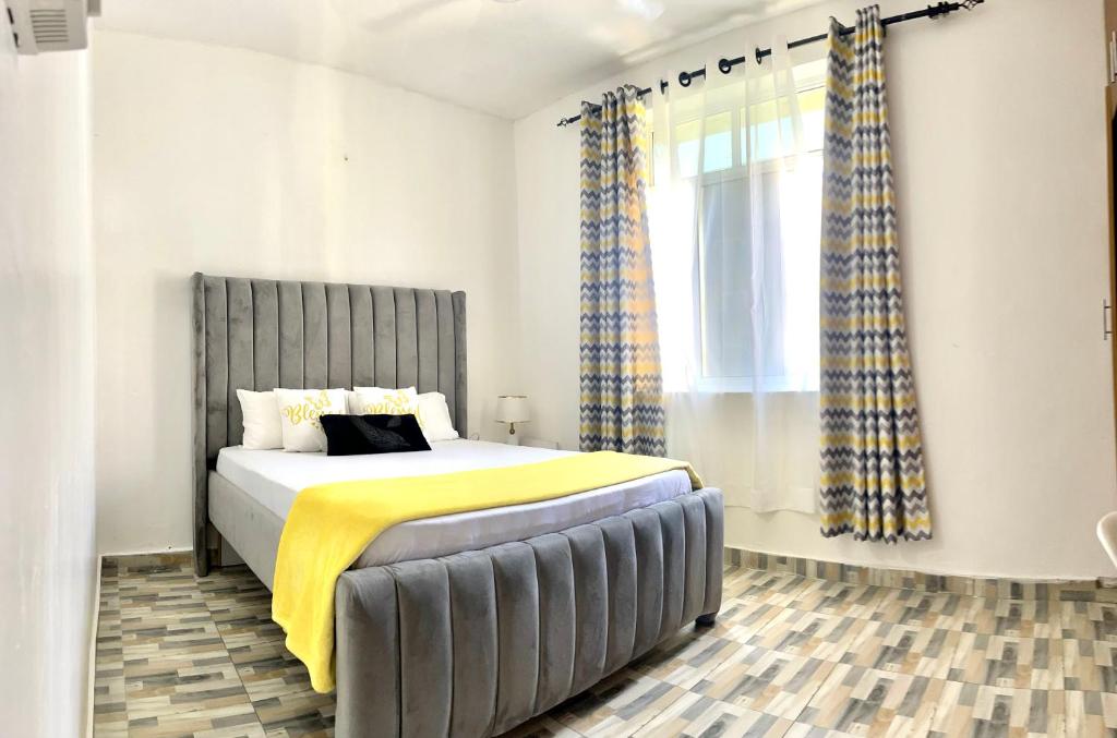 a bedroom with a bed with a yellow blanket at Unique apartment 2 in Mombasa