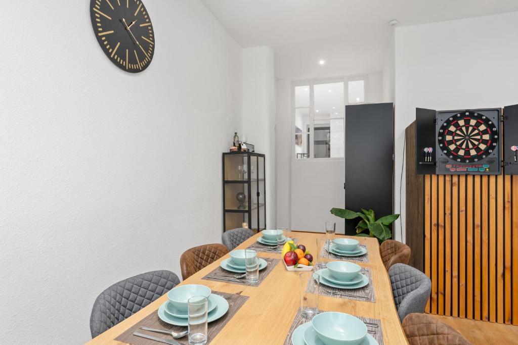une table à manger avec des chaises et une horloge murale dans l'établissement homey Apartments Park Suite, à Bremerhaven