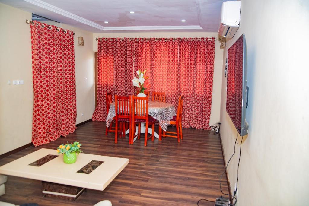 uma sala de jantar com cortinas vermelhas e uma mesa e cadeiras em EIREANN HOUSE Yassa em Douala