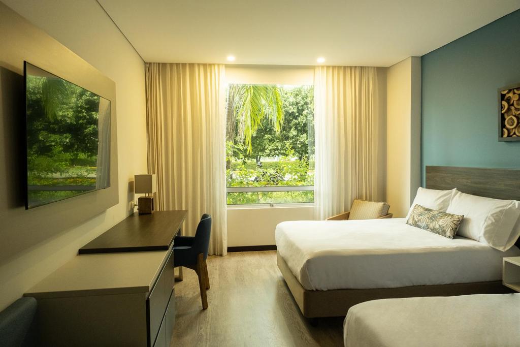ein Hotelzimmer mit 2 Betten, einem Schreibtisch und einem Fenster in der Unterkunft Hotel Morúa in Yopal