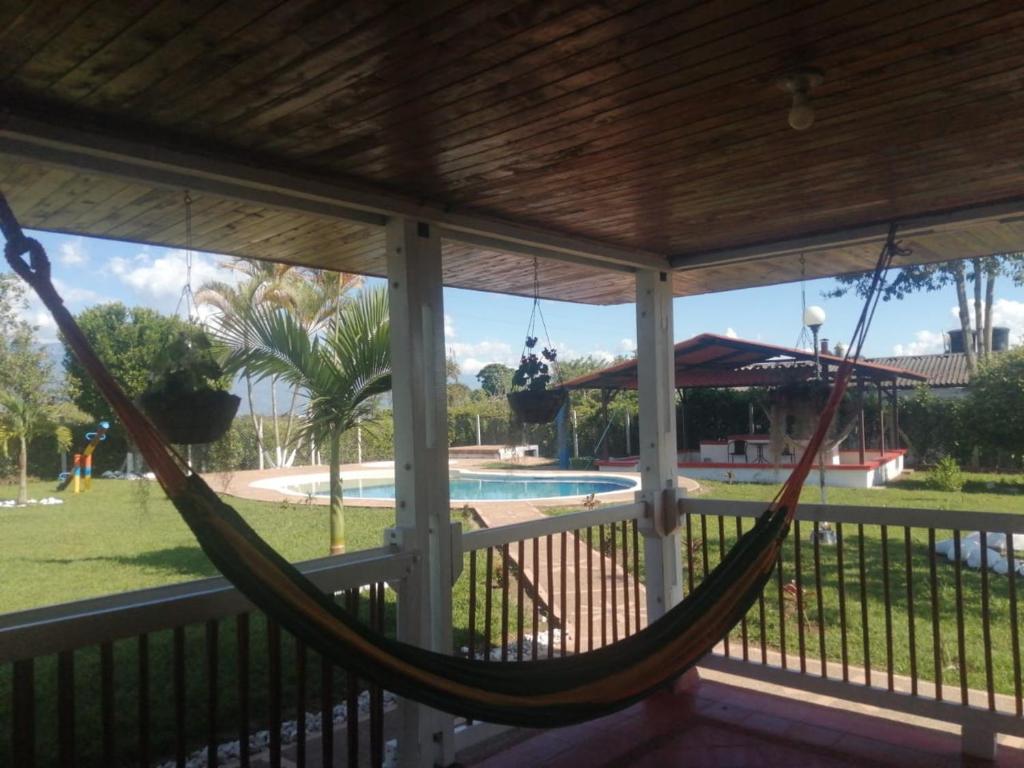 a hammock on a porch with a view of a pool at Alojamiento Campestre San Carlos in Montenegro