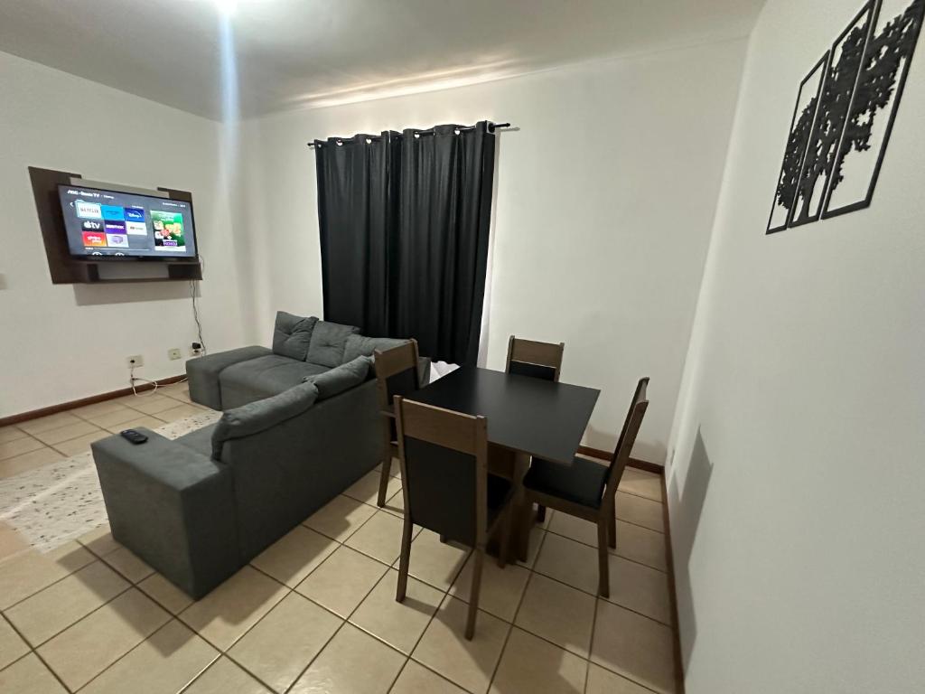 a living room with a couch and a table and a television at Pampulha 2 quartos completo in Belo Horizonte