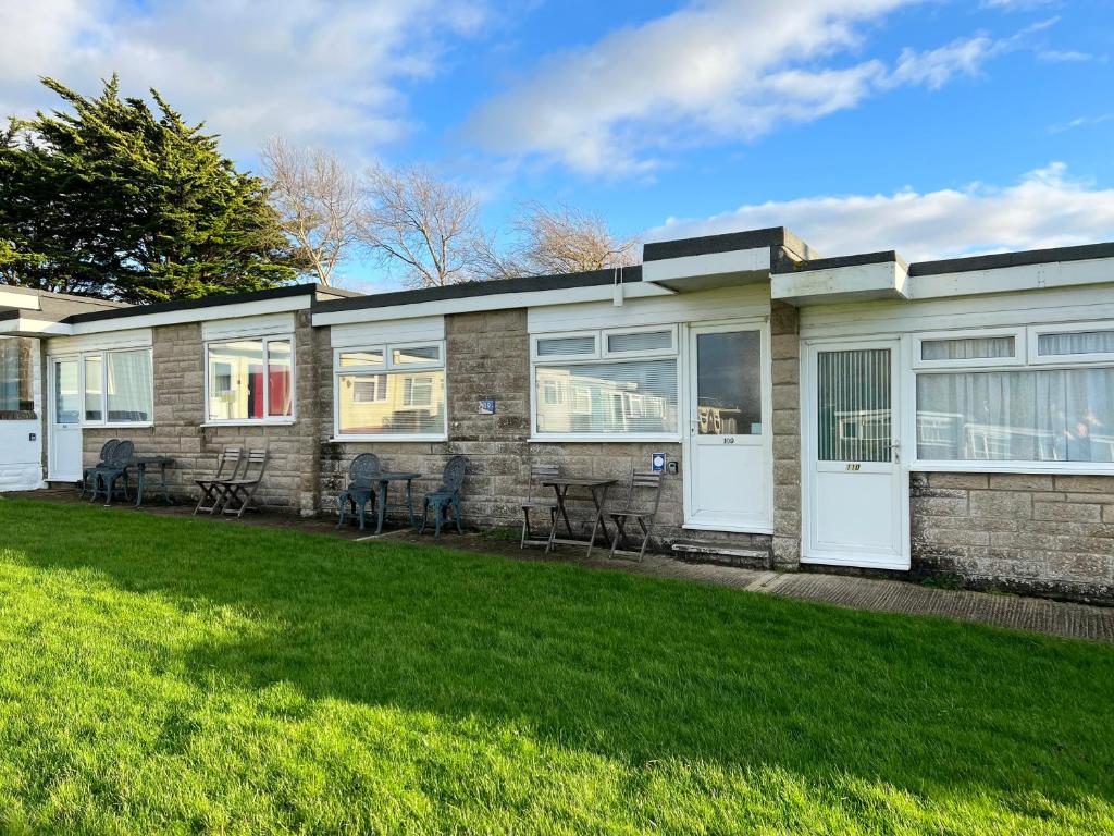 uma casa de tijolos com portas brancas e um quintal em 2 Bedroom Chalet SB109, Sandown Bay, Isle of Wight em Brading