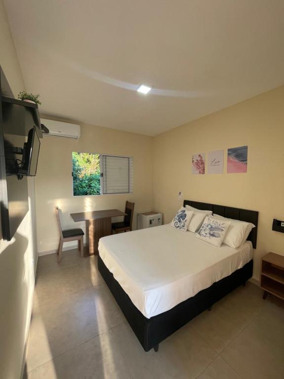 a bedroom with a bed and a table in it at Residencial 220 Maresias in Maresias