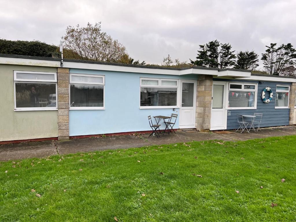 a blue house with a table and chairs in a yard at 2 Bedroom Chalet SB57, Sandown, Isle of Wight in Brading