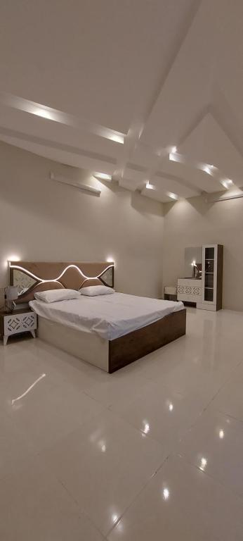 1 dormitorio con 1 cama grande en una habitación blanca en استراحة الأولين en Yeda