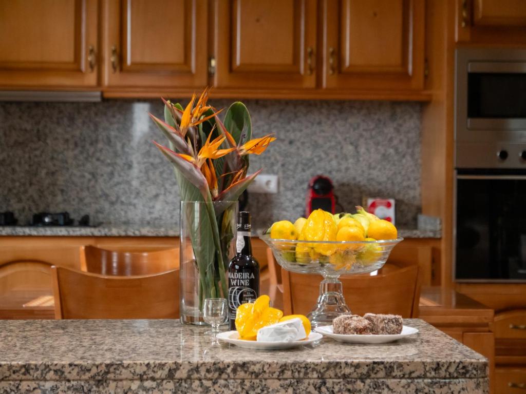 um balcão de cozinha com uma taça de fruta e um vaso de laranjas em The House of Passos em Ponta do Sol