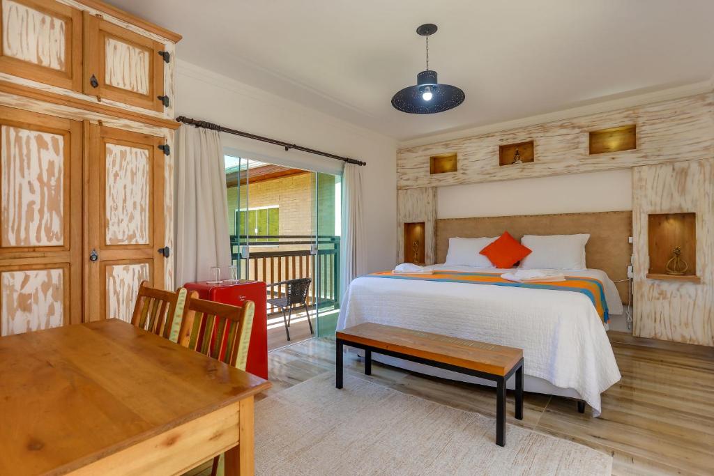 a bedroom with a bed and a table and a desk at Pousada Trem Chic in Poços de Caldas