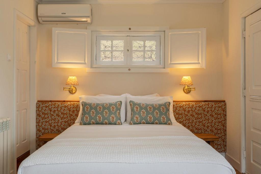 a bedroom with a bed with two pillows and a window at Quinta das Casas - Douro Winery & Villas in Vila Real