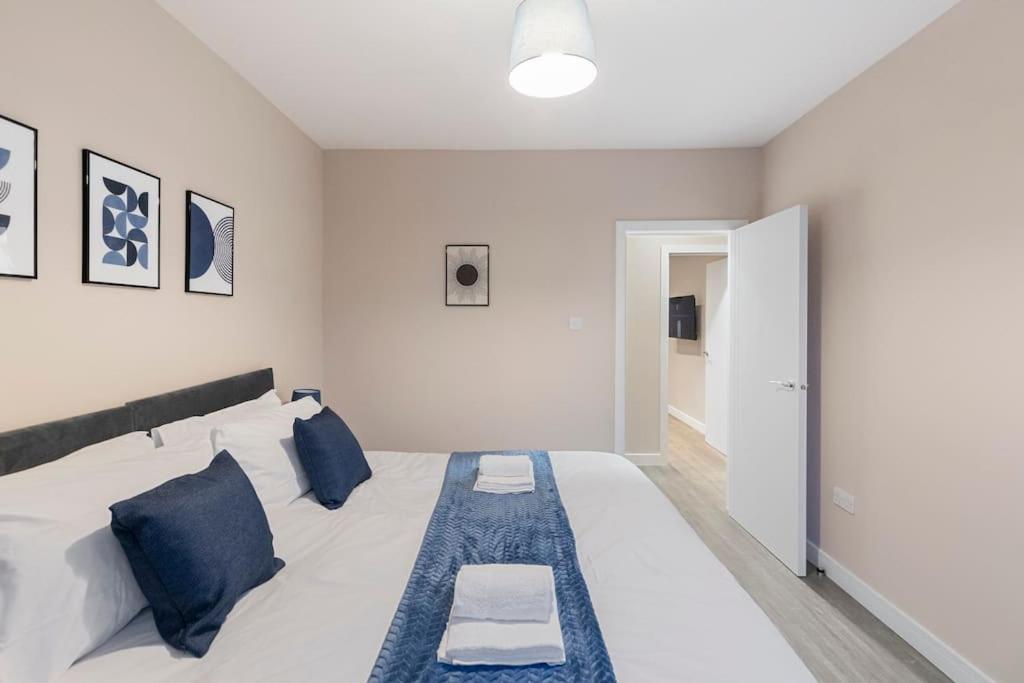 a bedroom with a large white bed with blue pillows at Convenient spacious house next Seven sisters station London in London