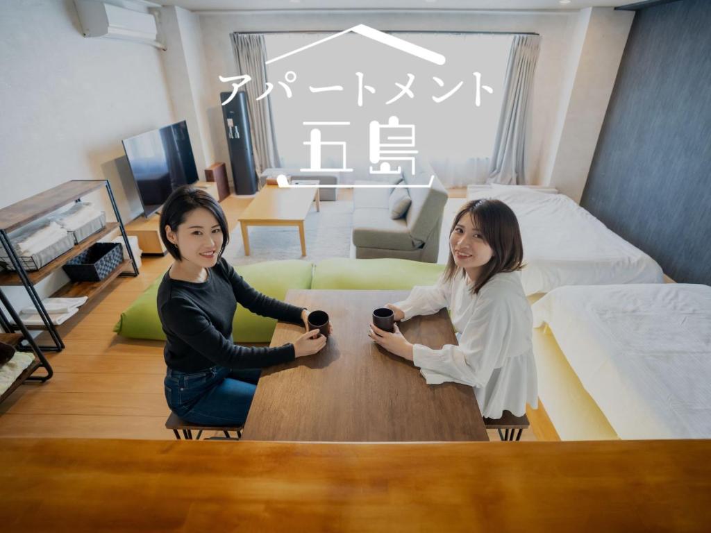 五島市にあるApartment Goto アパートメント五島の二人の女性が部屋のテーブルに座っている