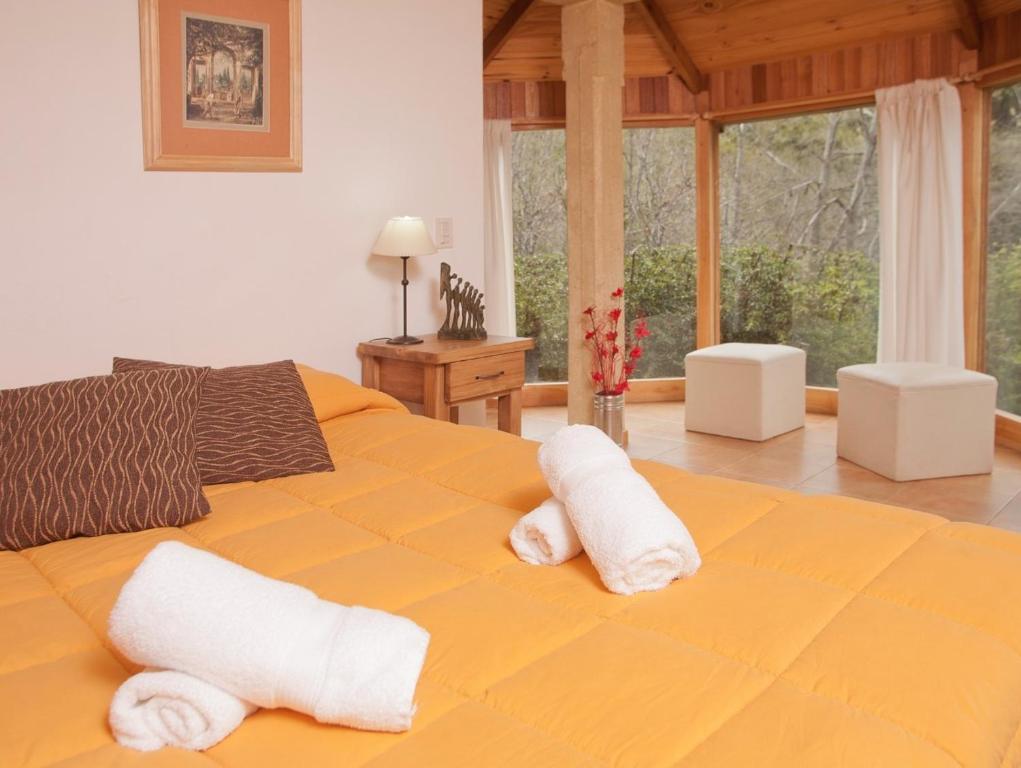 - une chambre avec un lit jaune et des serviettes dans l'établissement Cabañas Rucaleufu, à San Martín de los Andes