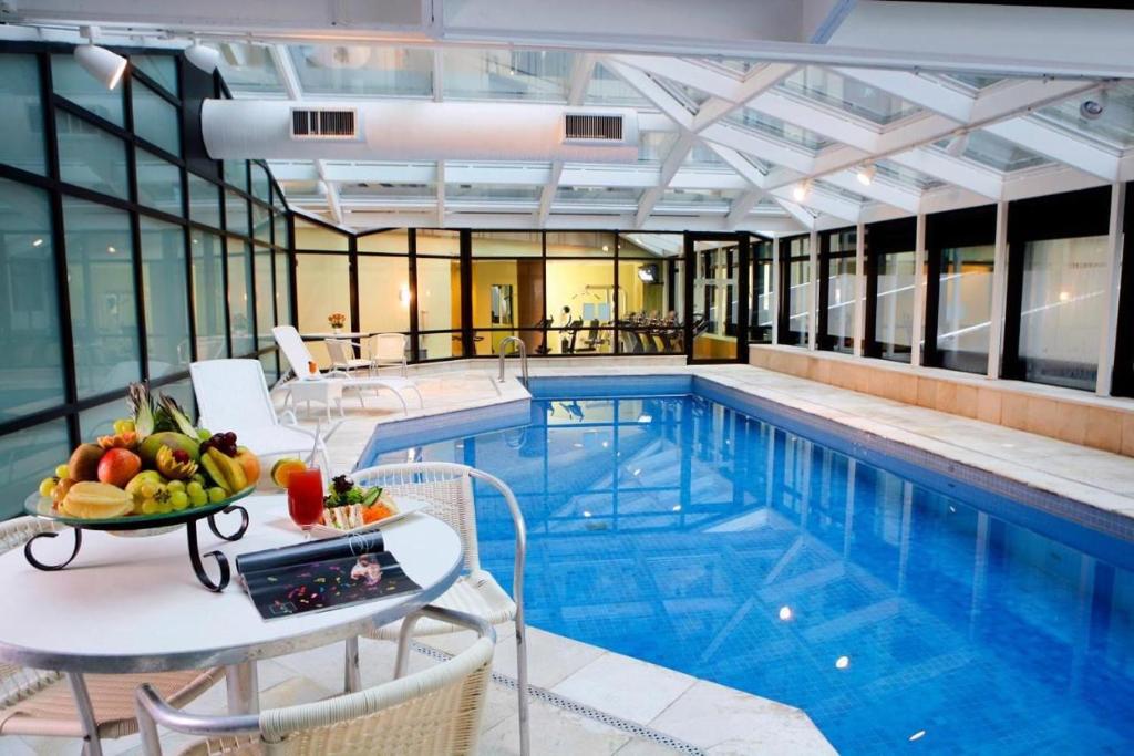 a hotel swimming pool with a table with fruit on it at Apart-hotel Bourbon São Paulo Ibirapuera Convention Hotel in Sao Paulo