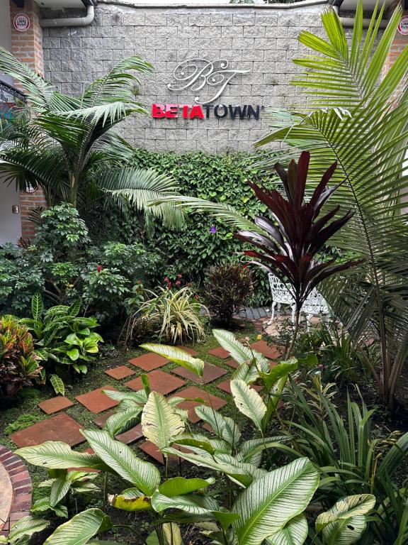 un jardín con plantas y una pared de ladrillo con un cartel en Beta Hotel, en Salento