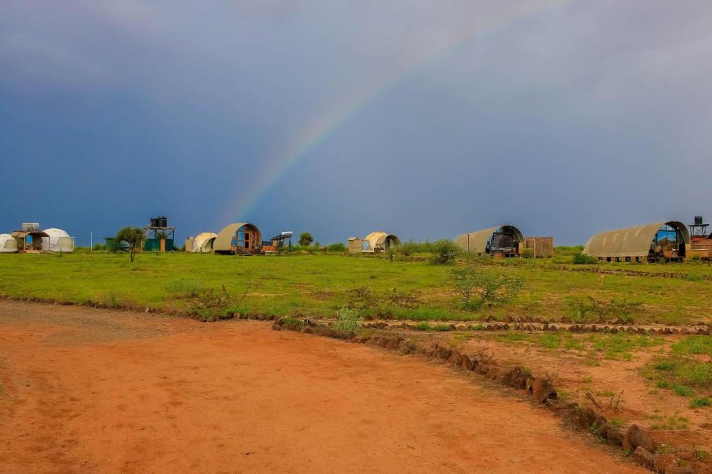 een regenboog in een veld met een groep koepels bij Little Amanya Camp in Amboseli