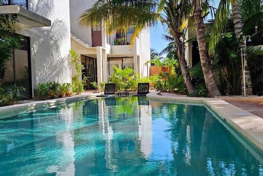 una piscina frente a una casa con palmeras en Villa Constantino en Telchac Puerto
