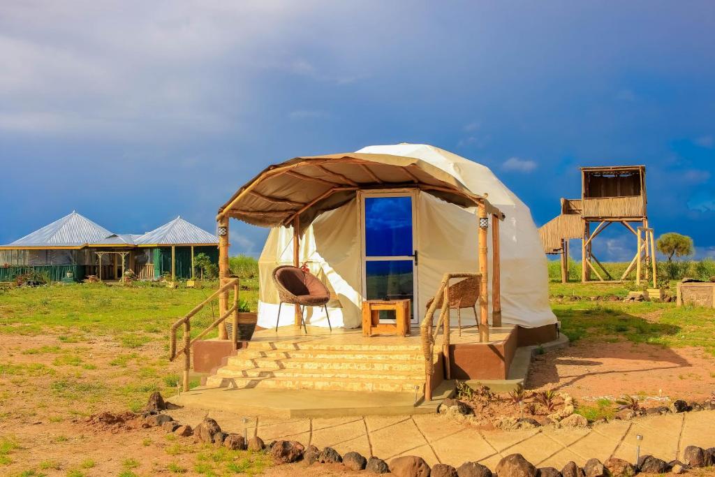 eine Jurte mit einer Treppe und Stühlen auf einem Feld in der Unterkunft Little Amanya Camp in Amboseli-Nationalpark