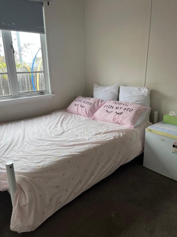 Un dormitorio con una cama con almohadas rosas y una ventana en Jennifer, en Warrane