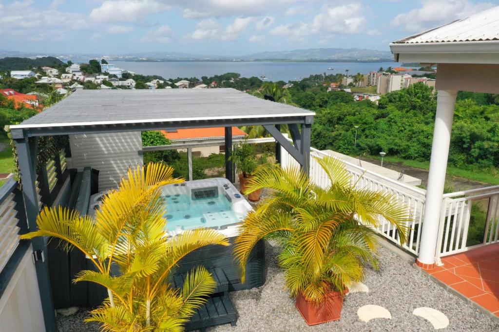 a balcony with a pool and palm trees on a house at Villa Sweet Caraïbes, vue mer, jacuzzi in Les Trois-Îlets