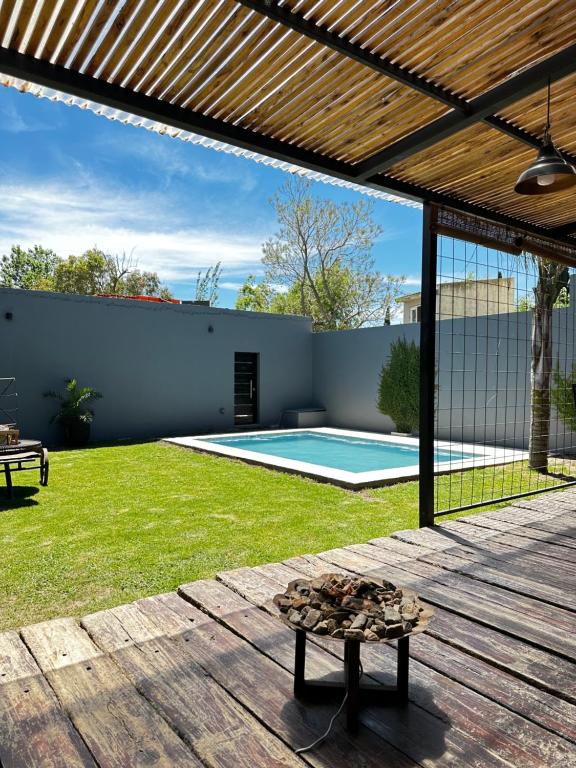 un patio trasero con piscina y terraza de madera en Chana's House en Chascomús