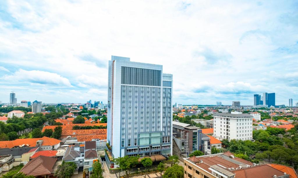 a tall white building in the middle of a city at Grand Swiss-Belhotel Darmo in Surabaya