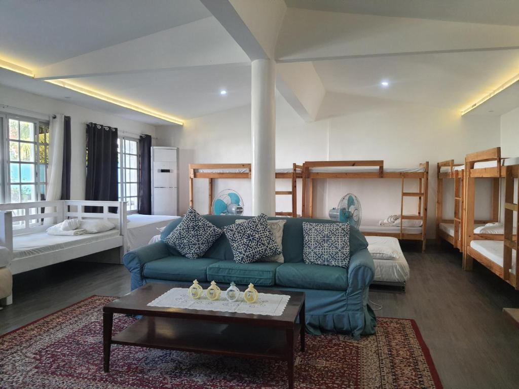 - un salon avec un canapé bleu et un lit dans l'établissement KUROSHARA Beach Resort, à Bolinao