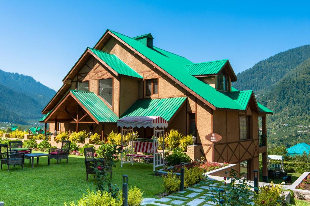 a house with a green roof on a lawn at The Anantmaya Resort in Manāli