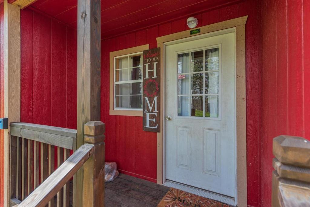 une maison rouge avec une porte blanche et une véranda dans l'établissement Tiny House at Buffalo River Lodge, à Saint Joe