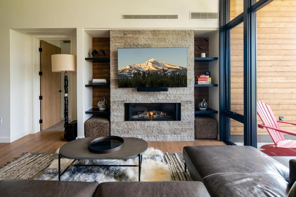 een woonkamer met open haard met uitzicht op de bergen bij 225 LakeLodge by Moonlight Basin Lodging in Big Sky