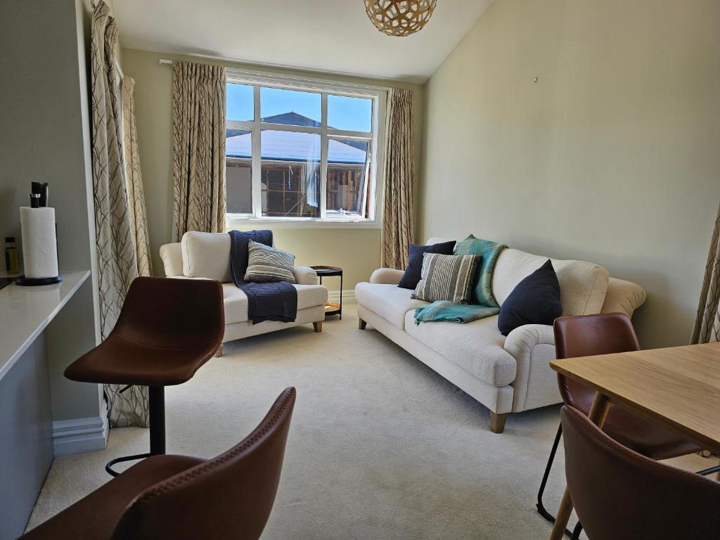 een woonkamer met 2 banken en een tafel bij Aspiring Villa Apartment in Christchurch