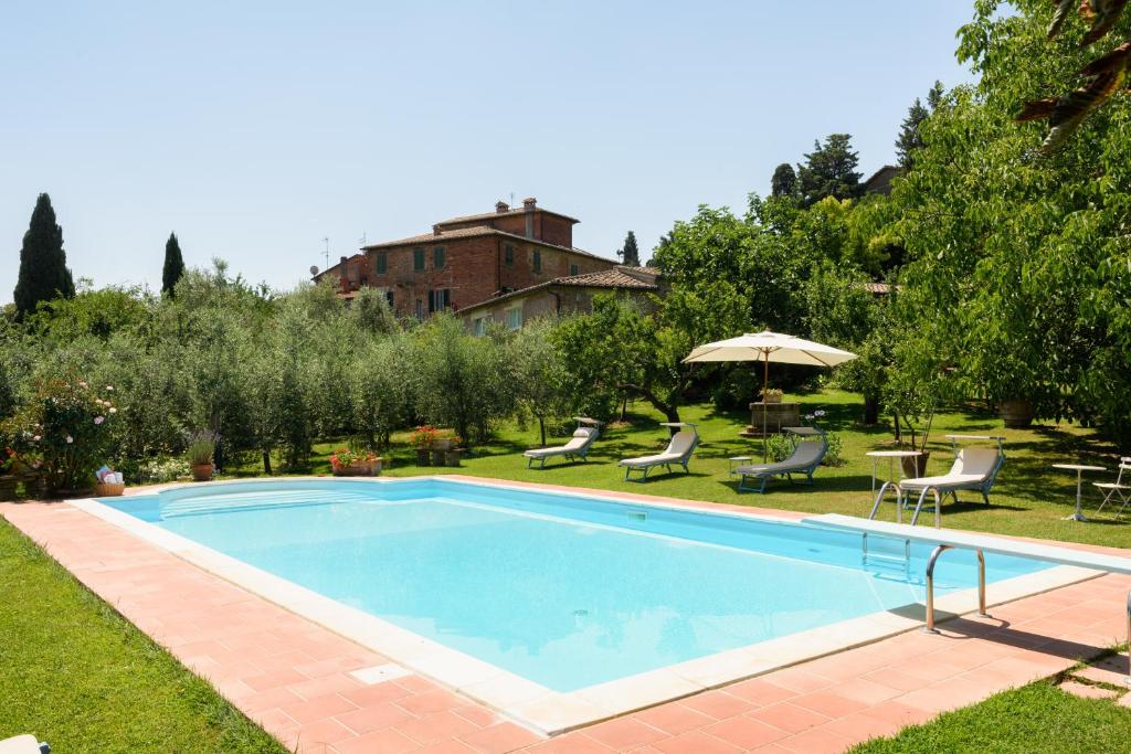 una piscina en un patio con sillas y sombrilla en Villa Vignacce - Boutique Country Resort, en Bettolle