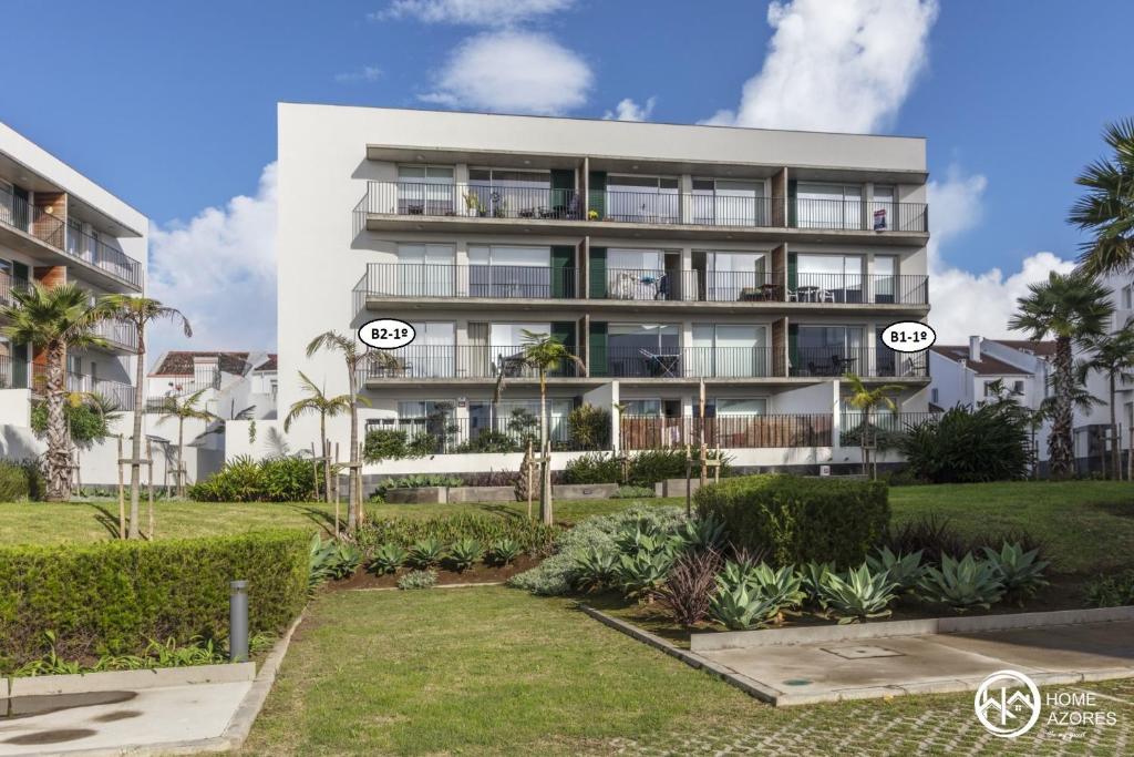 un gran edificio blanco con palmeras delante en Home Azores - Coliseu Residences, en Ponta Delgada