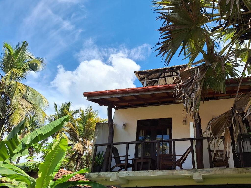 una casa con balcone con palme di Bandulas Beach House a Hikkaduwa