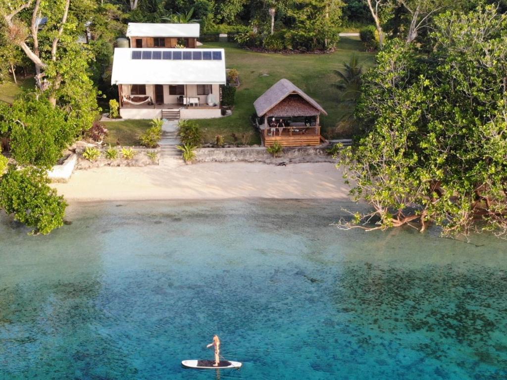 a man in a paddle board in the water next to a house at Aoredise in Luganville