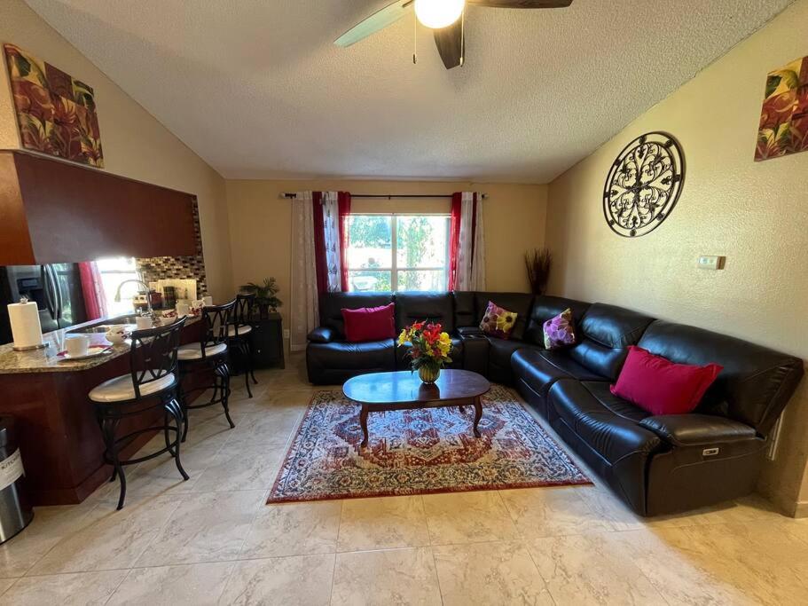 a living room with a black leather couch and a table at Beautiful Modern 3 BR House - Downtown Orlando in Orlando