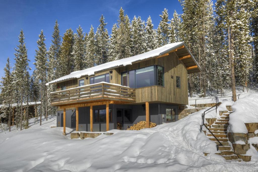 a house in the woods in the snow at 17 Lake Cabin by Moonlight Basin Lodging in Big Sky