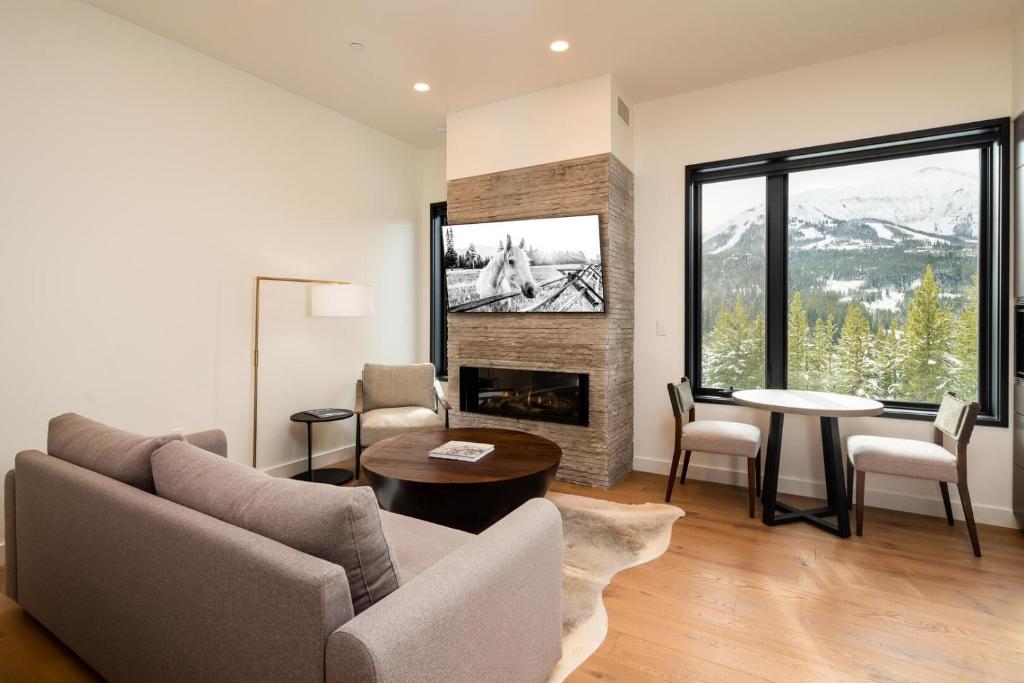 ein Wohnzimmer mit einem Sofa, einem Tisch und einem Kamin in der Unterkunft 223 LakeLodge by Moonlight Basin Lodging in Big Sky