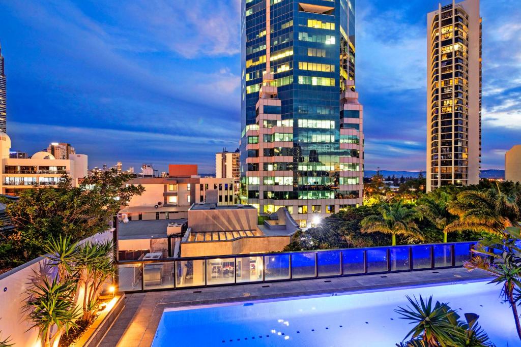 een uitzicht op de skyline van de stad 's nachts met een zwembad bij Pool View, Low Floor Apartment at Circle on Cavill - Wow Stay in Gold Coast