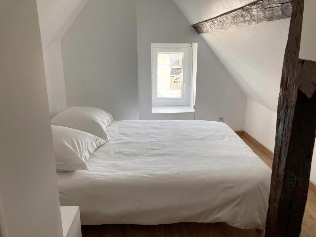 a white bed in a room with a window at Vue sur la cathédrale - Au cœur de Bourges in Bourges