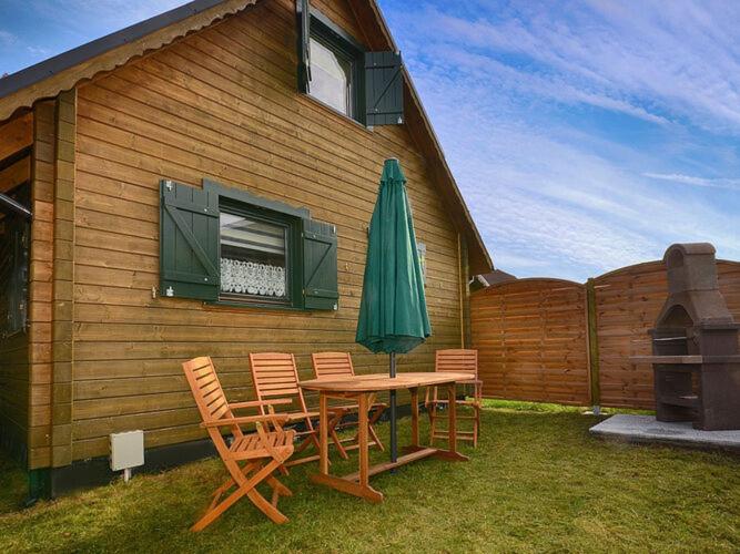 a patio with a table and chairs and an umbrella at Comfortable holiday house with a garden, D bki in Dąbki
