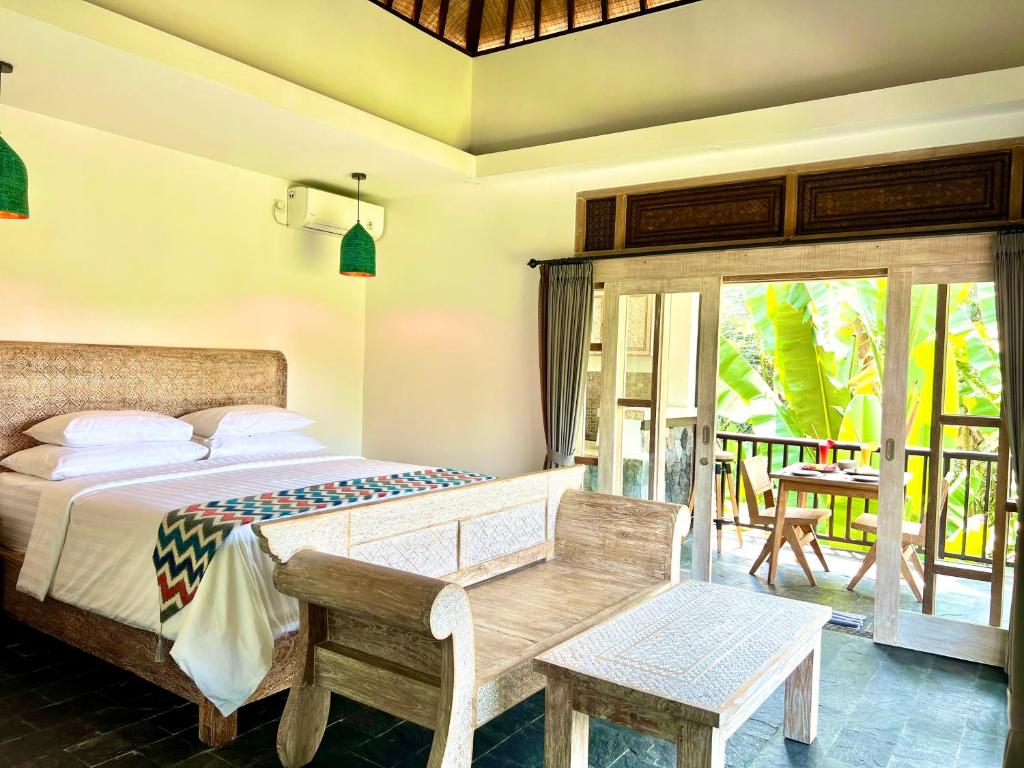 a bedroom with a bed and a balcony with a table at Widya Luxury House in Ubud
