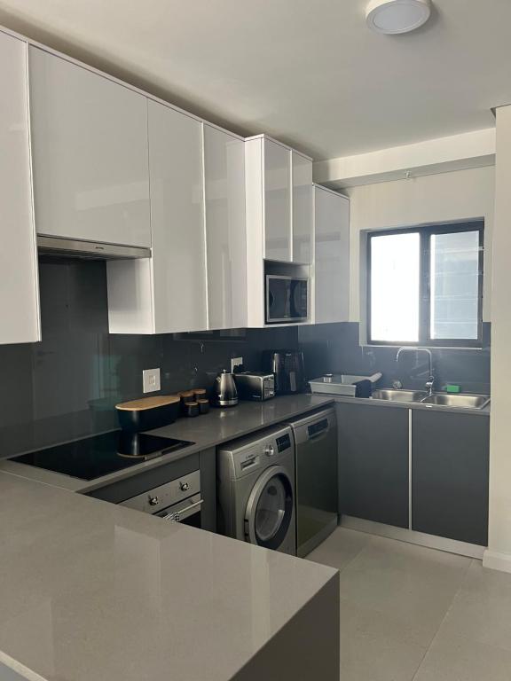 a kitchen with white cabinets and a washer and dryer at Flat 2 Block 15 Bellamare in Port Elizabeth