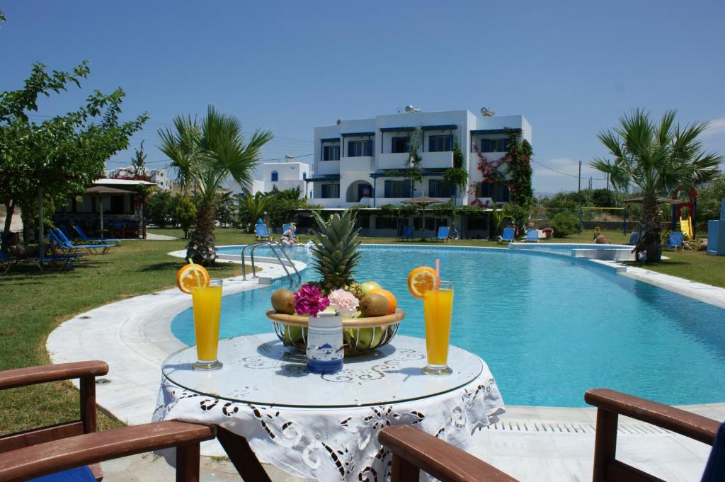 a table with fruit and drinks next to a swimming pool at Colosseo Star in Agios Prokopios