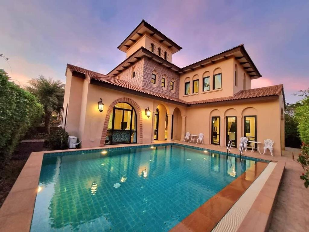 a swimming pool in front of a house at Chivani Pattaya in Na Jomtien