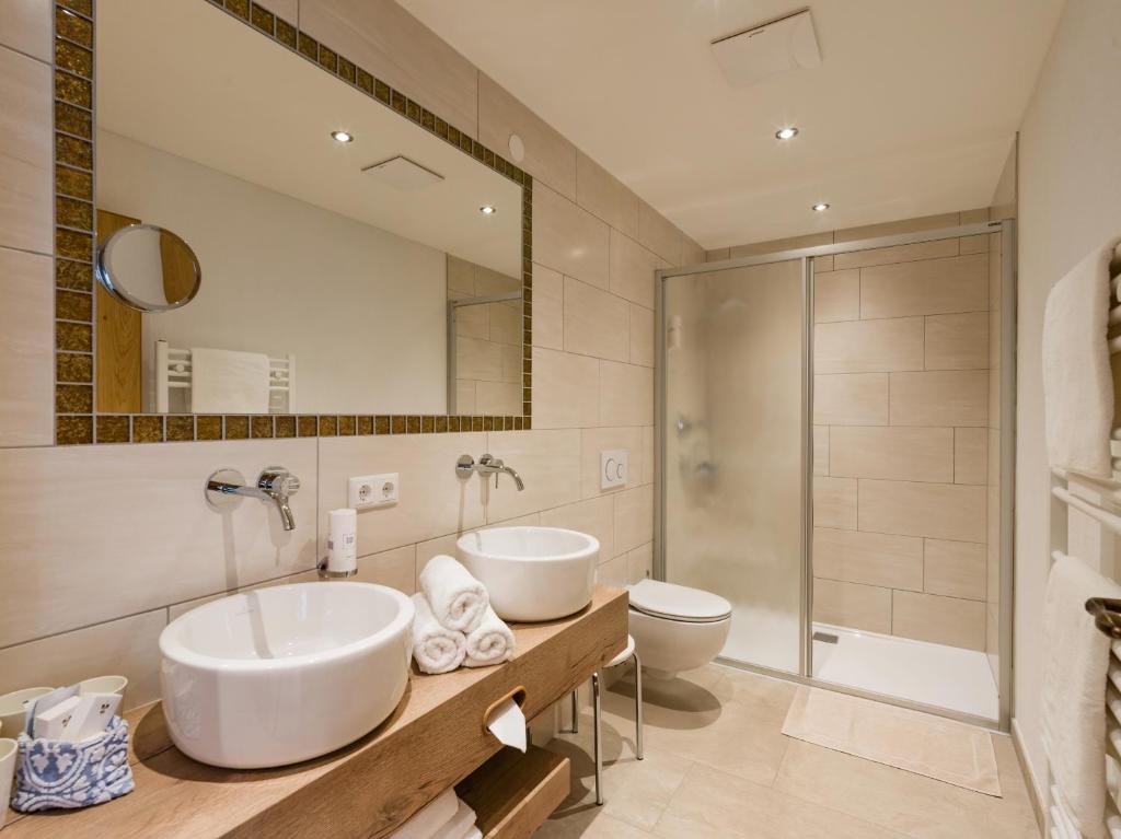 un bagno con due lavandini, un water e uno specchio di Hotel Feichter a Söll