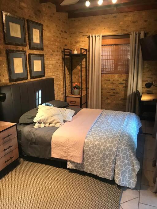 a bedroom with a bed and a brick wall at Kyasaja Home away from home in Pretoria