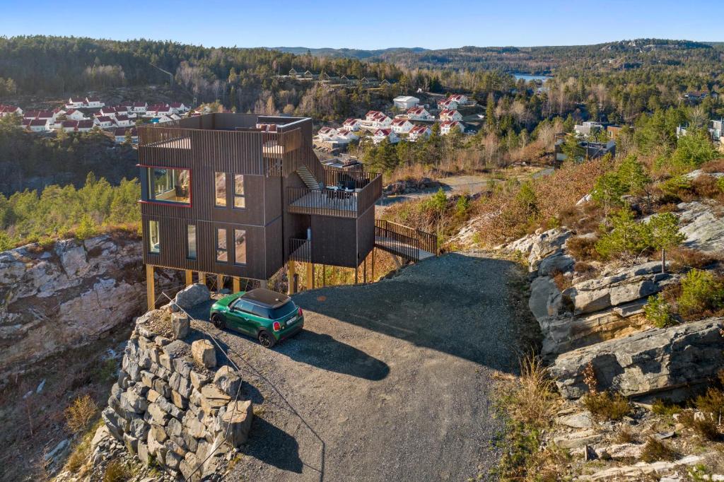 a house on top of a hill with a green car at Cabin with sea, lake and hill view in Søndeled