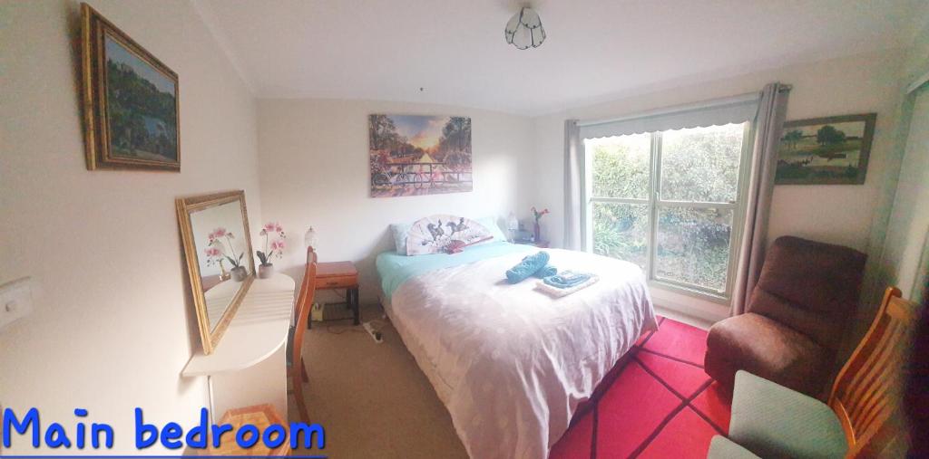 a bedroom with a bed and a desk and a window at Daylesford A Very Quiet ABELIA COTTAGE BOTANICAL COTTAGE 10 min walk town in Daylesford