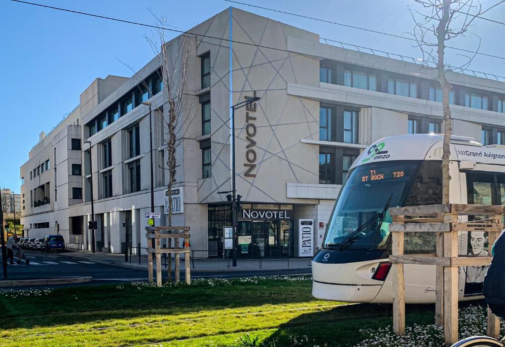 un tren está estacionado frente a un edificio en Novotel Avignon Centre, en Aviñón