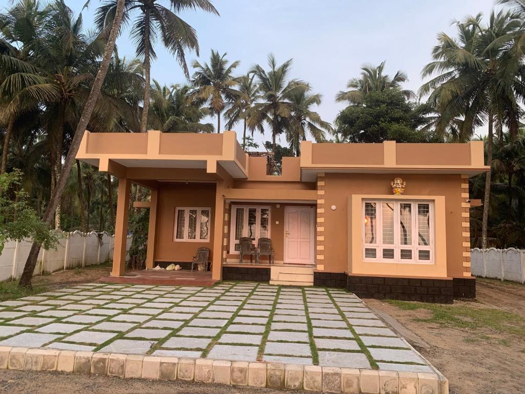 a small house in front of some palm trees at Casa Ganesha beach residence in Irimbranallūr